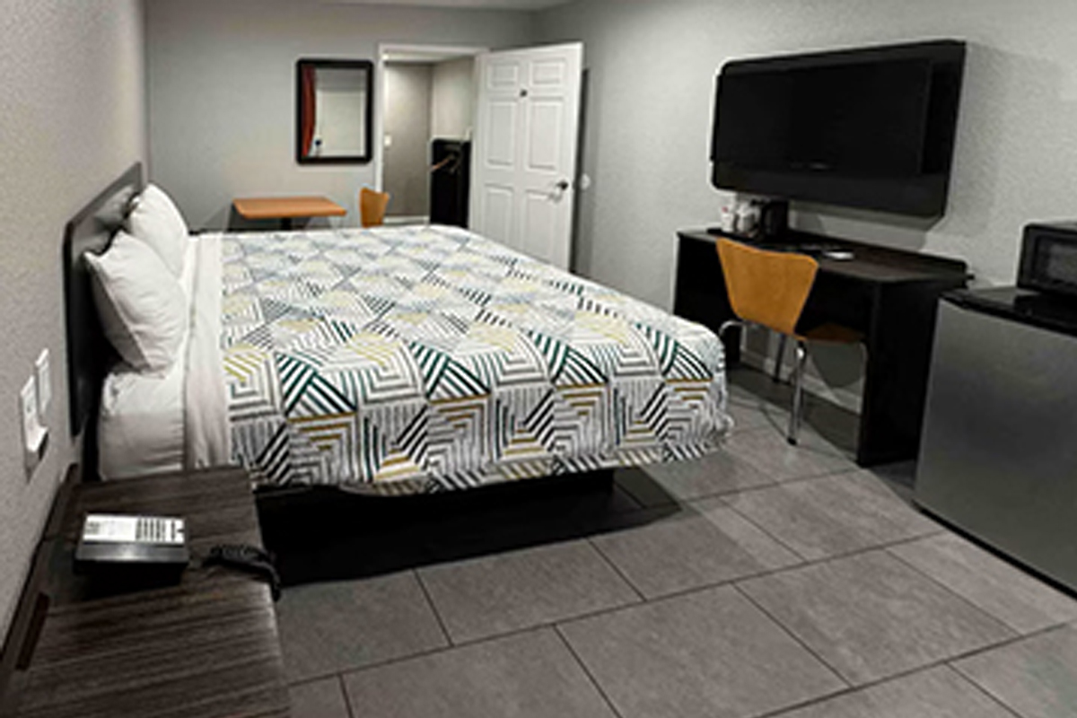 Guest room with one bed, desk, television and micro-fridge
